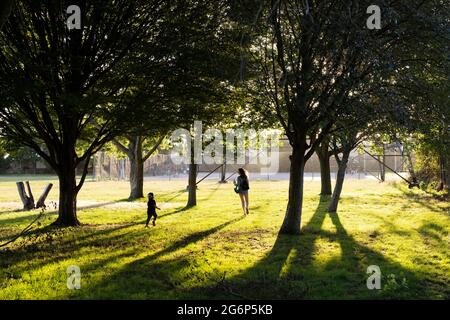 Eine Mutter und ein Kind jagen sich unter Bäumen Stockfoto