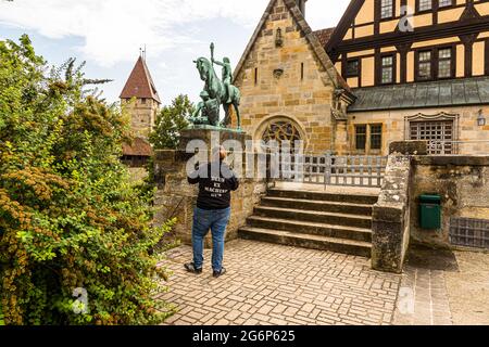 Lutherdenkmal auf der Veste Coburg, Skulptur Licht und Macht (Lightbringer zu Pferd, 1913) von Hans Klett (* 1876) in Coburg, Deutschland. Auf dem T-Shirt eines Besuchers steht: Deus ex Machine Gun Stockfoto