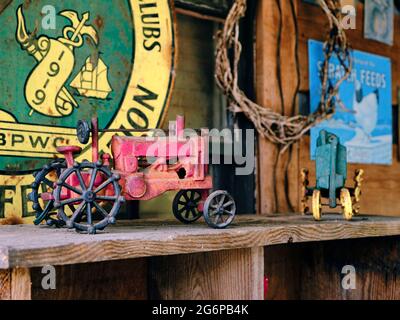 Alte Vintage-Spielzeug-Traktor aus antikem Metall auf einem staubigen Regal. Stockfoto