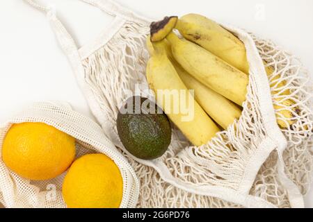 Frisches Obst, Gemüse in Öko-Baumwollbeuteln auf einem beigen Tisch. Karotten, Orangen, Bananen, Avocado vom Markt. Zero Waste Shopping-Konzept. Stockfoto