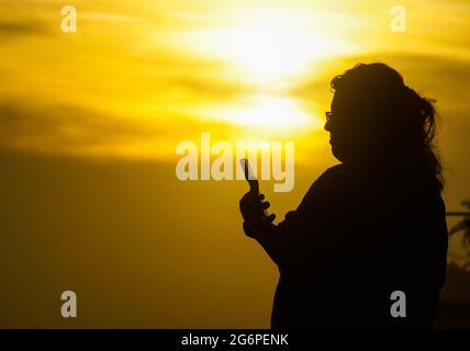 San Salvador, El Salvador. Juli 2021. Eine Frau überprüft ihr Handy am Strand von San Marcelino während des Sonnenuntergangs. (Foto von Camilo Freedman/SOPA Images/Sipa USA) Quelle: SIPA USA/Alamy Live News Stockfoto