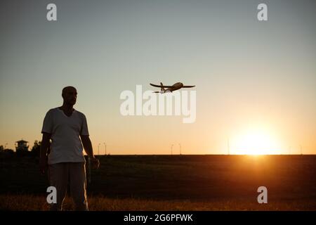 Weicher Fokus von Vater und Sohn spielen Spielzeug Flugzeug in der Wiese bei Sonnenuntergang mit glücklichen Emotionen. Familien-, Urlaubs- und Reisekonzept. Bei Sonnenuntergang im Sommer starten sie ein Flugzeug vor dem Hintergrund des Himmels Stockfoto