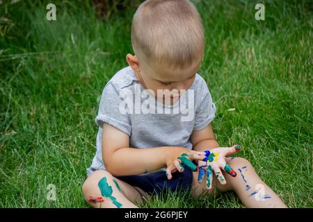 Das Kind zeichnet ein Muster auf das Bein. Eine lustige Zeichnung mit hellen Farben auf dem Körper. Selektiver Fokus Stockfoto