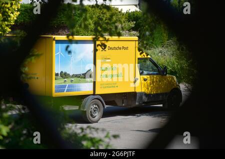 Leipziger Land, Deutschland. Juni 2021. Ein Lieferwagen der Deutschen Post mit der grünen Aufschrift „natürlich natürlich. Das Fahrzeug läuft mit Strom' steht in einem Dorf in der Leipziger Landschaft, eingerahmt von grünen Büschen und Bäumen. Quelle: Volkmar Heinz/dpa-Zentralbild/ZB/dpa/Alamy Live News Stockfoto