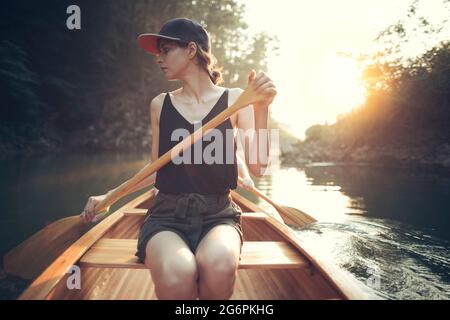 Junge Frau paddelt Kanu auf einem Waldsee Stockfoto