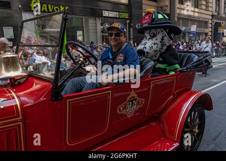 NEW YORK, NY - 07. JULI: Während der Ticker Tape Parade der „Hometown Heroes“ am 07. Juli 2021 in New York City fährt ein Hundefeuerwehr mit einem alten FDNY-Auto. Im Canyon of Heroes in Manhattan werden Mitarbeiter des Gesundheitswesens, Ersthelfer und wichtige Mitarbeiter für ihren Dienst während der Covid-19-Pandemie geehrt. Stockfoto