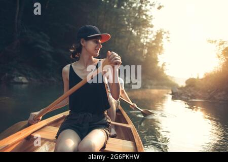 Junge Frau genießt Kanufahren auf einem Waldsee Stockfoto