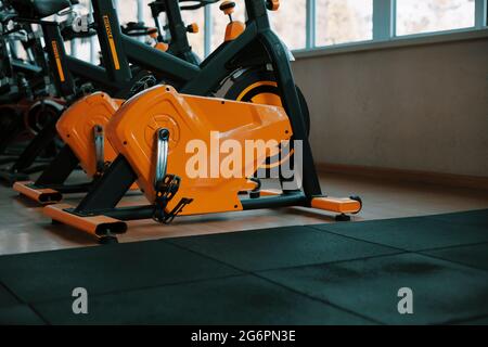 Fitnessclub mit einem orangen Trainingsfahrrad. Nahaufnahme Stockfoto