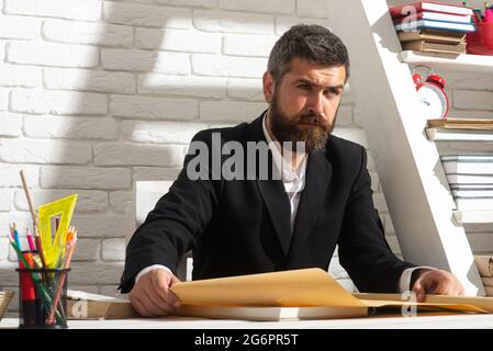 Porträt eines ernsthaften Lehrers im Klassenzimmer. Tutor, Professor, Mentor Mann am Schreibtisch. Studium, Lernen, Trainingskonzept. Stockfoto