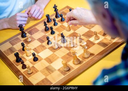 Wardenburg, Deutschland. Juli 2021. Ein Spieler legt ein hölzernes Schachstück auf ein Schachbrett. Chess ist ein strategisches Brettspiel, bei dem zwei Spieler abwechselnd Schachfiguren auf einem Schachbrett bewegen. Das Ziel des Spiels ist es, den Gegner zu kaschieren, das heißt, seinen König so anzugreifen, dass er weder verteidigen noch entkommen kann. Quelle: Hauke-Christian Dittrich/dpa/Alamy Live News Stockfoto