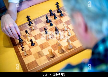 Wardenburg, Deutschland. Juli 2021. Ein Spieler legt ein hölzernes Schachstück auf ein Schachbrett. Chess ist ein strategisches Brettspiel, bei dem zwei Spieler abwechselnd Schachfiguren auf einem Schachbrett bewegen. Das Ziel des Spiels ist es, den Gegner zu kaschieren, das heißt, seinen König so anzugreifen, dass er weder verteidigen noch entkommen kann. Quelle: Hauke-Christian Dittrich/dpa/Alamy Live News Stockfoto