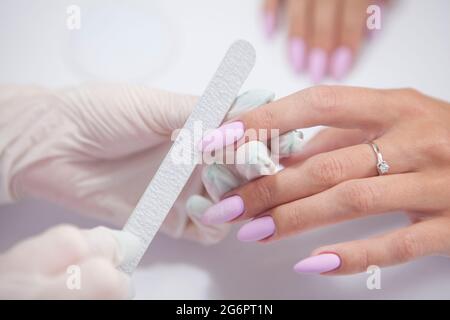 Nahaufnahme der Manikuristen Feilung Nägel der weiblichen Klientin Stockfoto