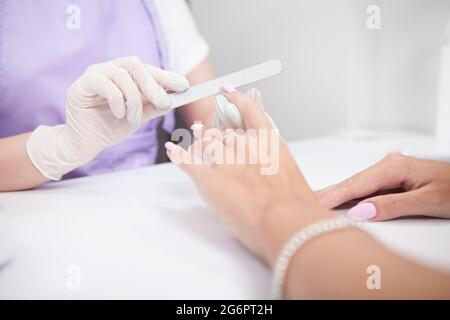 Beschnitten Nahaufnahme der professionellen Manikuristin Feilen Nägel der weiblichen Klientin Stockfoto