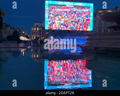 Die Euro 2020-Fan-Zone-Leinwand in London zeigt ein Spiel aus Italien und Spanien und eine Reflexion im Trafalgar Square-Brunnen. Stockfoto