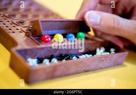 Wardenburg, Deutschland. Juli 2021. Während einer Runde des Spiels „Mastermind“ legt ein Spieler farbige Spielsteine auf das Spielfeld. Mastermind ist ein Logikspiel für zwei Personen, bei dem eine Farbfolge durch aufeinanderfolgende Vermutungen bestimmt werden soll. Quelle: Hauke-Christian Dittrich/dpa/Alamy Live News Stockfoto