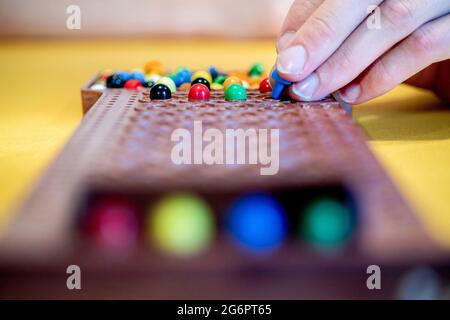 Wardenburg, Deutschland. Juli 2021. Während einer Runde des Spiels „Mastermind“ legt ein Spieler farbige Spielsteine auf das Spielfeld. Mastermind ist ein Logikspiel für zwei Personen, bei dem eine Farbfolge durch aufeinanderfolgende Vermutungen bestimmt werden soll. Quelle: Hauke-Christian Dittrich/dpa/Alamy Live News Stockfoto