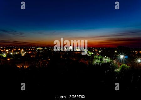 Abendpanorama der Stadt auf dem Hintergrund des Sonnenuntergangs mit einem blau-kastanienbraunen Himmel.der Horizont Linie bei Morgendämmerung in den roten Himmel.Panorama der Stadt mit dem Stockfoto