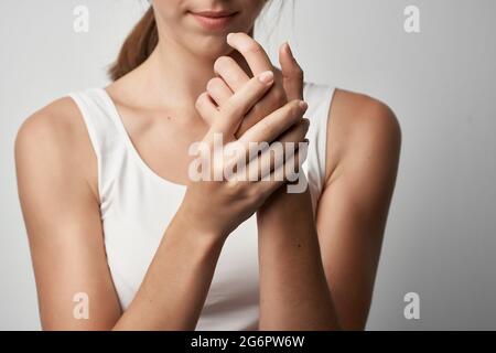 Frau in weißem T-Shirt hält Hand Gesundheitsprobleme chronische Schmerzen Stockfoto