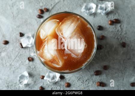 Glas Eiskaffee, Bohnen und Eis auf einem grauen Tisch mit Struktur Stockfoto