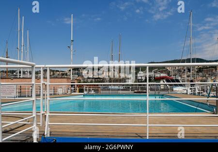 Das Schwimmbad im Alten Hafen (Porto Antico) von Genua mit dem Hafen und der Stadt im Hintergrund im Sommer, Ligurien, Italien Stockfoto