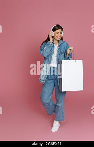 Glückliche, schöne Frau mit Kopfhörern und Einkaufstaschen Stockfoto