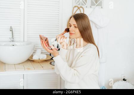 Frau, die neben dem Waschbecken sitzt und sich schminkt Stockfoto