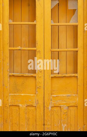Porträtansicht einer gelben Tür und restaurierungsbedürftigen Fensterläden in einer Stadt, Portugal Stockfoto