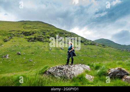 Ein Spaziergänger unter den Munro-Bergen von Ben More (links) und Stob Binnein (rechts) bei Crianlarich, Schottland, von Benmore Glen aus gesehen Stockfoto