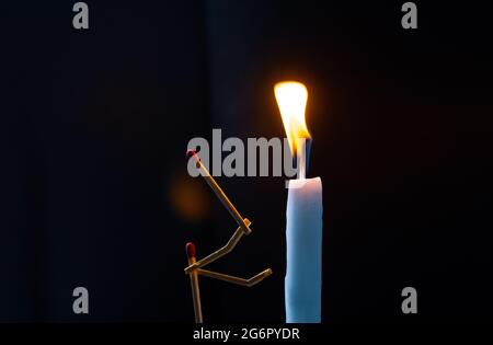 Streichhölzer in Form eines Mannes, der eine Kerze anzündet, Streichhölzer, der eine Kerze anzündet. Stockfoto