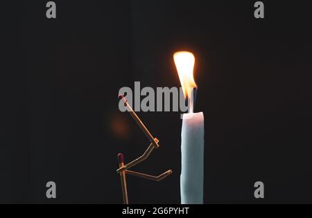 Streichhölzer in Form eines Mannes, der eine Kerze anzündet, Streichhölzer, der eine Kerze anzündet. Stockfoto