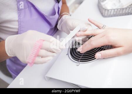 Nahaufnahme eines Manikuristen, der Nägel eines Kunden filterte Stockfoto
