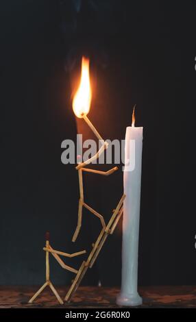 Streichhölzer in Form eines Mannes, der eine Kerze anzündet, Streichhölzer, der eine Kerze anzündet. Stockfoto