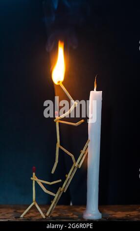 Streichhölzer in Form eines Mannes, der eine Kerze anzündet, Streichhölzer, der eine Kerze anzündet. Stockfoto