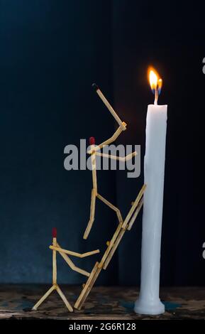 Streichhölzer in Form eines Mannes, der eine Kerze anzündet, Streichhölzer, der eine Kerze anzündet. Stockfoto