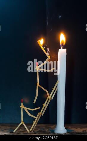 Streichhölzer in Form eines Mannes, der eine Kerze anzündet, Streichhölzer, der eine Kerze anzündet. Stockfoto