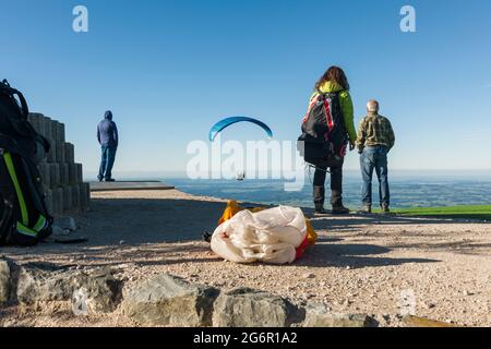 Schwangau, Deutschland - 11. Oktober 2017: Gleitschirme auf dem Tegelberg am Startplatz sehen anschließend einen gerade gestarteten Segelflieger. Stockfoto