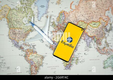 SWANSEA, Großbritannien - 19. JUNI 2021: Smartphone mit Expedia App-Logo mit Flugzeugspielzeug auf der Weltkarte im Hintergrund. Reise-Anwendung, Urlaubsplanung Stockfoto
