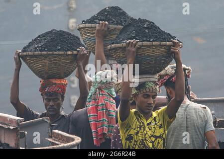 Eine menschliche Kette von Trägern trägt Kohle, Sand und Kies von den Bargen, die an der Aminbazar Landing Station am Buriganga River außerhalb von Dhaka festgemacht sind. Bangladesch absolviert derzeit den Abschluss der LDC-Kategorie (am wenigsten entwickelte Länder), was zum großen Teil der extrem harten Arbeit billiger Arbeitskräfte zu verdanken ist. Ein Portier macht zwischen 80 und 140 USD pro Monat, laut den Websites paylab.com und averagesalarysurvey.com Stockfoto