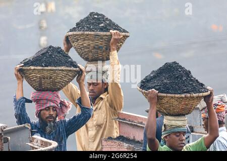 Eine menschliche Kette von Trägern trägt Kohle, Sand und Kies von den Bargen, die an der Aminbazar Landing Station am Buriganga River außerhalb von Dhaka festgemacht sind. Bangladesch absolviert derzeit den Abschluss der LDC-Kategorie (am wenigsten entwickelte Länder), was zum großen Teil der extrem harten Arbeit billiger Arbeitskräfte zu verdanken ist. Ein Portier macht zwischen 80 und 140 USD pro Monat, laut den Websites paylab.com und averagesalarysurvey.com Stockfoto