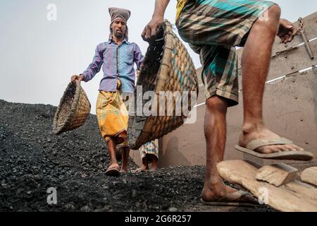 Eine menschliche Kette von Trägern trägt Kohle, Sand und Kies von den Bargen, die an der Aminbazar Landing Station am Buriganga River außerhalb von Dhaka festgemacht sind. Bangladesch absolviert derzeit den Abschluss der LDC-Kategorie (am wenigsten entwickelte Länder), was zum großen Teil der extrem harten Arbeit billiger Arbeitskräfte zu verdanken ist. Ein Portier macht zwischen 80 und 140 USD pro Monat, laut den Websites paylab.com und averagesalarysurvey.com Stockfoto