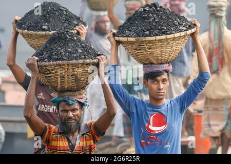 Eine menschliche Kette von Trägern trägt Kohle, Sand und Kies von den Bargen, die an der Aminbazar Landing Station am Buriganga River außerhalb von Dhaka festgemacht sind. Bangladesch absolviert derzeit den Abschluss der LDC-Kategorie (am wenigsten entwickelte Länder), was zum großen Teil der extrem harten Arbeit billiger Arbeitskräfte zu verdanken ist. Ein Portier macht zwischen 80 und 140 USD pro Monat, laut den Websites paylab.com und averagesalarysurvey.com Stockfoto