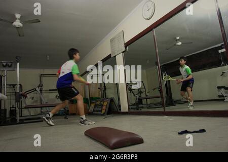 Ein junger Badmintonathlet übt verschiedene Schläge und Schritte vor einem großen Spiegel im Jaya Raya Badmintonclub in Jakarta, Indonesien. Stockfoto