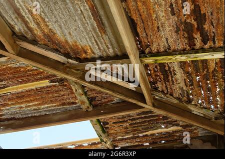 Ein Gebäude ist in Verfall geraten, der Himmel kann durch ein Loch in seinem Wellblechdach gesehen werden. Stockfoto