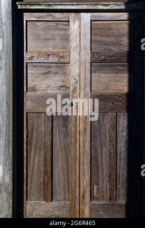 Eine schwere, hölzerne, getäfeltes Tür leuchtet in der Sonne. Es hat einen runden Türknauf. Stockfoto