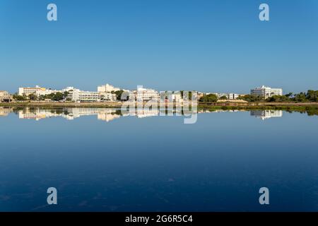 Allgemeiner Blick auf die mallorquinische Stadt Colonia de Sant jordi bei Sonnenaufgang spiegelt sich im Teich der Salzwerke wider Stockfoto