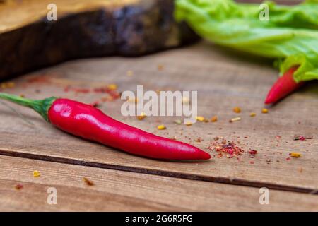 Rote, scharfe Chilischoten mit Gewürzen auf einem hölzernen Hintergrund. Mini-Pfeffer. Nahaufnahme Stockfoto