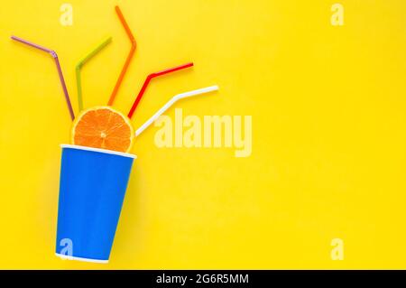 Schneiden Sie Orange in einen blauen Eimer aus Papier mit bunten Trinkhalmen für den Sommerdrink. Stockfoto