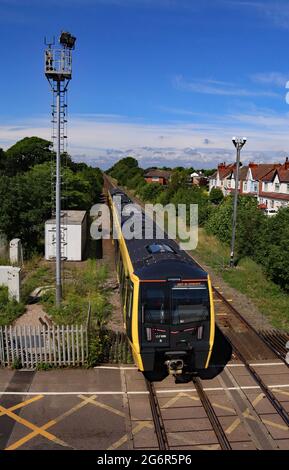 Einer der neuen Mersey Rail Züge, gebaut von Stadler, überquert den Bahnübergang, als er am 6.7.2021 den Bahnhof Ainsdale in der Nähe von Southport verlässt Stockfoto