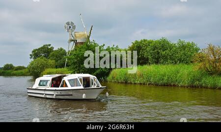 Broads Cruiser auf der Ant am How Hill Norfolk mit Windmühle - Windpumpe im Hintergrund. Stockfoto