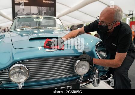 Chris Bailey, Leiter der Fahrzeugpräsentation bei Bonhams, reinigt ein 1964 Aston Martin DB5-Cabriolet, das im Bonhams Saleroom im Goodwood Estate, Chichester, West Sussex, das zuvor Prinzessin Margaret und Lord Snowdon gehörte, und dem Schauspieler Peter Sellers ausgestellt wird. Und wird geschätzt, £1.3-1.5 Millionen in der Bonhams Festival of Speed Sale am Freitag zu holen. Bilddatum: Donnerstag, 8. Juli 2021. Stockfoto